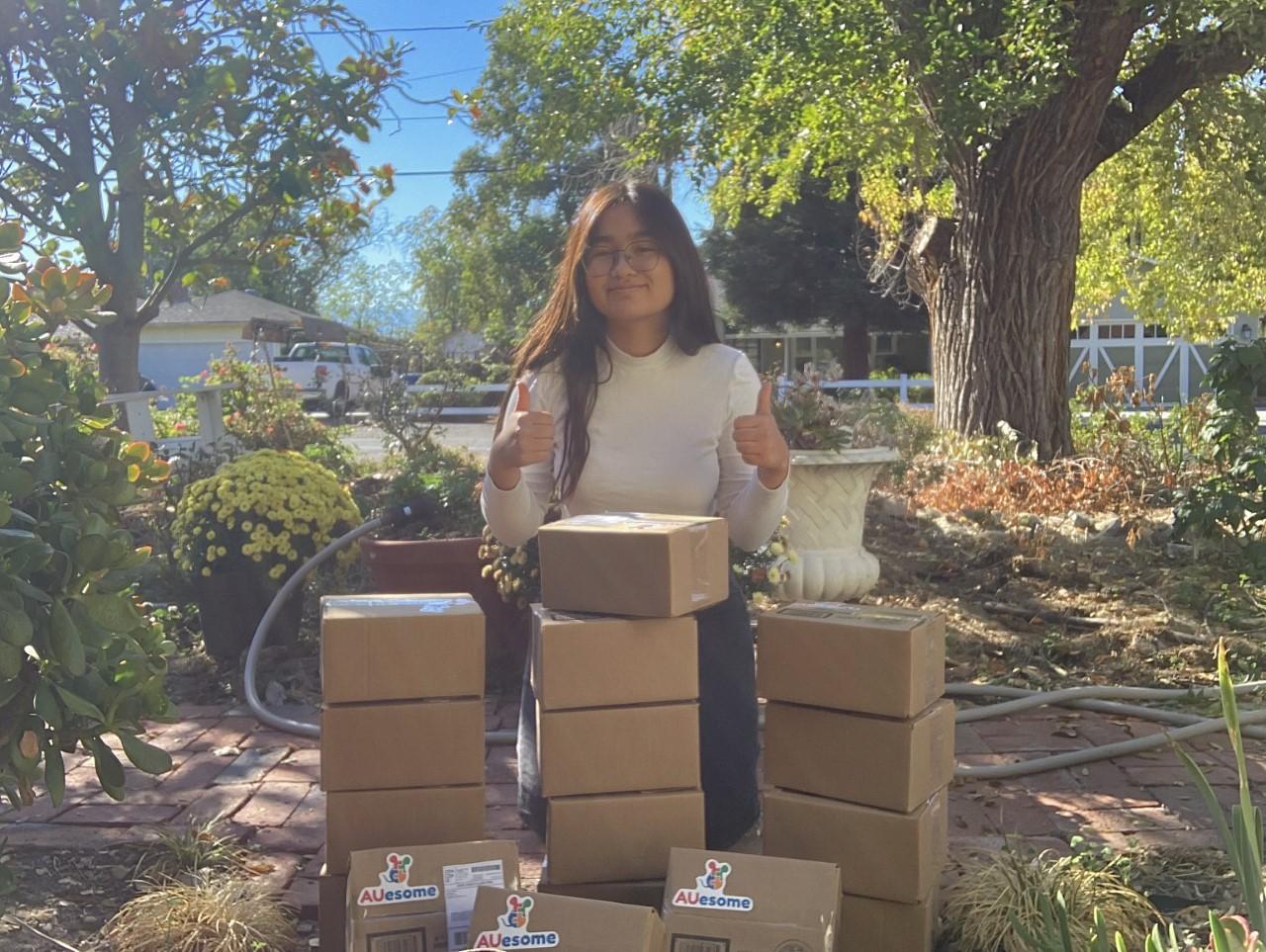 Anne standing with AUesome therapy kits in small cardboard boxes